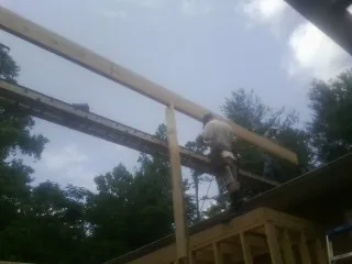 Carpenter setting a ridge beam over a new addition frame — Ice Dam Removal by Roofing Brothers in Ossipee