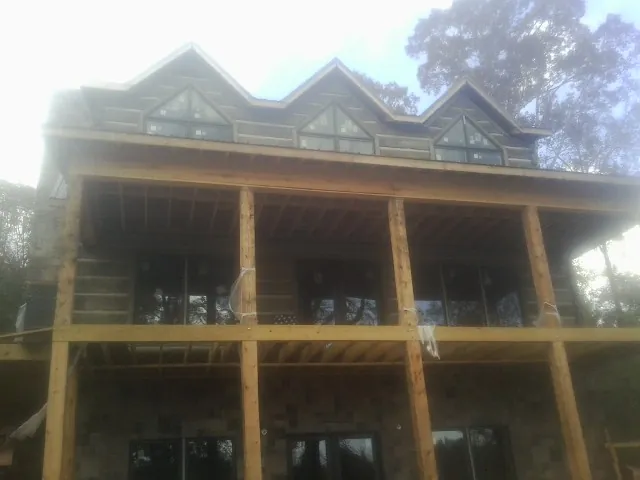 Dormers and porch framing on a large log home under construction — Roof Coating work by our crew in Ossipee