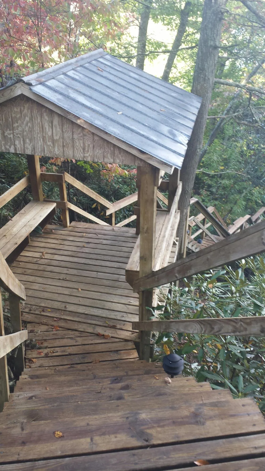 Metal roofed shelter over wooden steps on a wooded walkway — Skylight Repair & Installation work by our crew in Ossipee