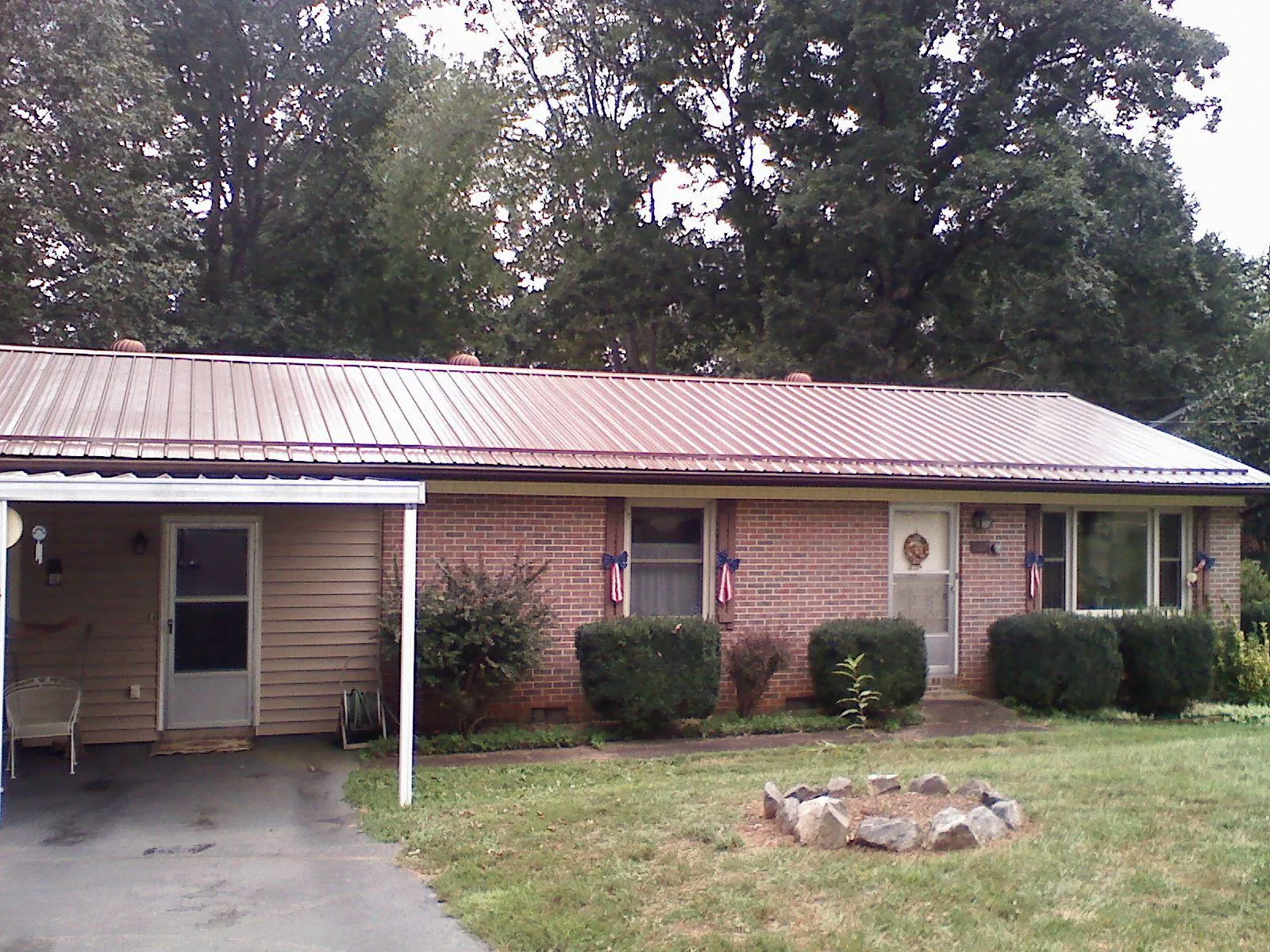 Bronze metal roof and carport on a brick ranch home — Roof Repair work by our crew in Ossipee