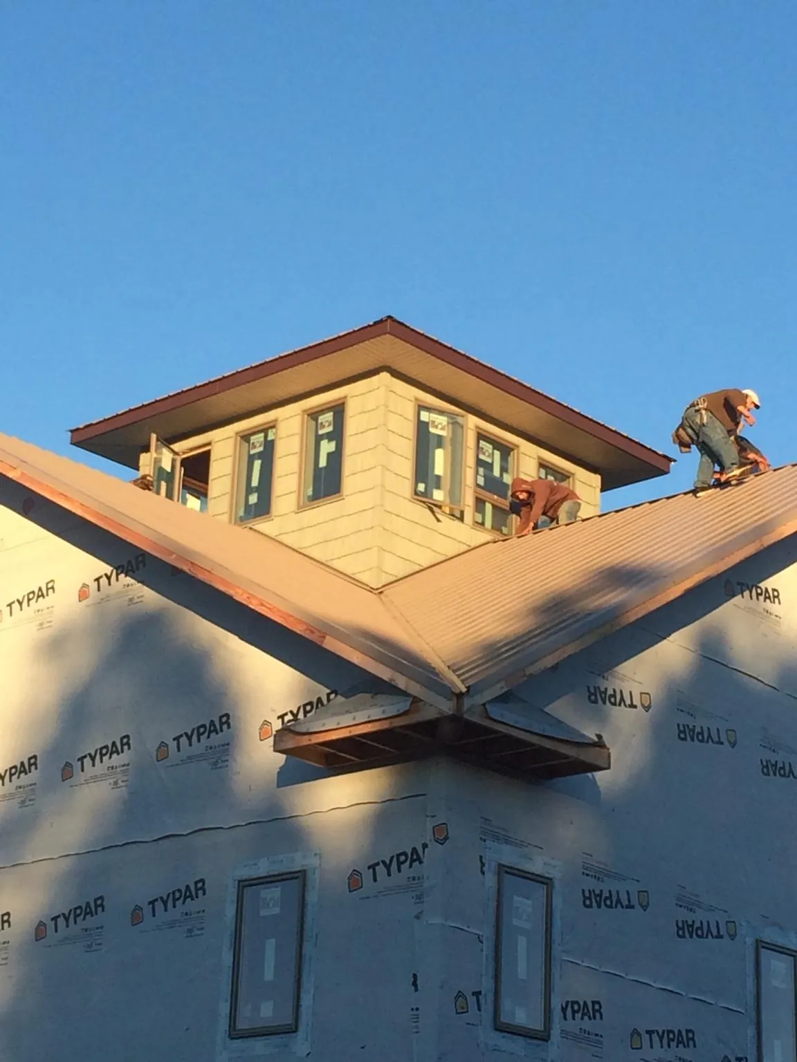 Roofers working around a rooftop cupola on a new metal roof at sunset — Roof Waterproofing in Ossipee by Roofing Brothers